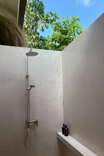 a shower in a bathroom with a white wall at Madi House in Matara