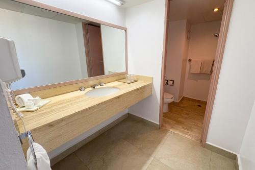 a bathroom with a sink and a large mirror at LXHotel Condomar in Puerto Vallarta