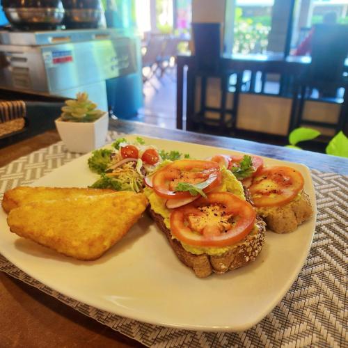 a plate of food with toast and tomatoes on it at Lanta Mermaid Boutique House in Ko Lanta