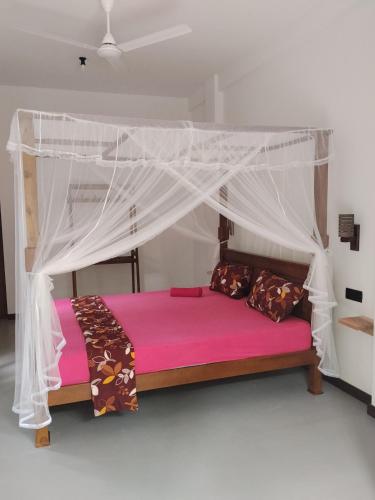 a bed with a canopy in a room at Serenity Lodge in Ahangama