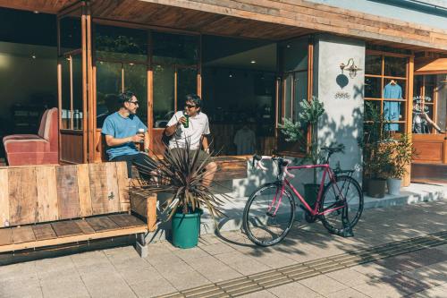 two men standing outside of a building with a bike at Charlie's Bed in Wakayama