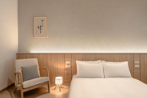 a bedroom with a white bed and a chair at HOYU INN's in T'ien-liao