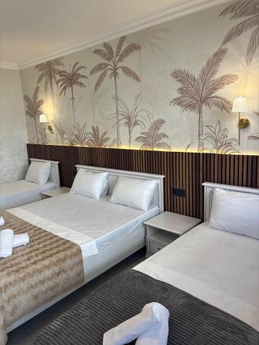 two beds in a room with palm trees on the wall at Palmen Villa Gabala in Gabala