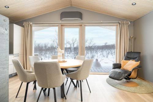 una sala da pranzo con tavolo, sedie e una finestra di Villa Naali E a Kilpisjärvi