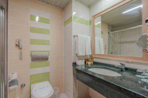 a bathroom with a sink and a mirror and a toilet at Sural Resort Hotel in Side