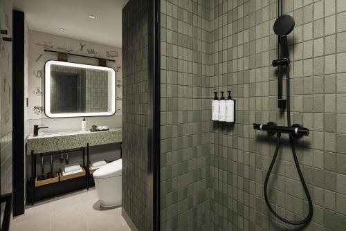 a bathroom with a shower with a toilet and a mirror at Caption By Hyatt Kabutocho Tokyo in Tokyo