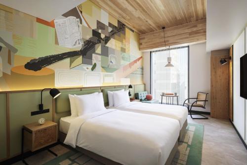 a hotel room with two white beds and a wall with a guitar at Caption By Hyatt Kabutocho Tokyo in Tokyo