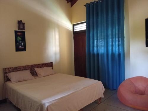 a bedroom with a bed and a blue curtain at Samee Villa & Hostel Airport in Seeduwa