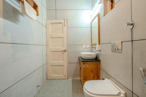 a small bathroom with a toilet and a sink at SaffronStays Tirthan House - Balcony View in Bandal