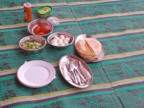 Una mesa con platos y utensilios y cuencos de comida. en Ayed Wadi Rum camp, en Wadi Rum