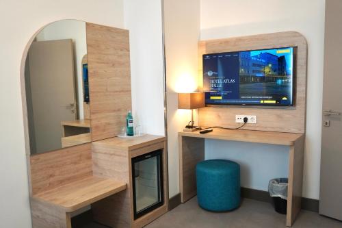 een kamer met een spiegel, een tv en een bureau bij Hotel Atlas Halle in Halle an der Saale