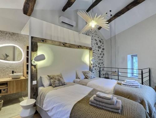 two beds in a bedroom with a mirror and a sink at La Clède du PontNeuf in Valleraugue