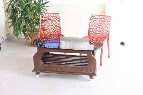 a glass table with two chairs and a laptop on it at Aakruthi Homestay in Dāvangere