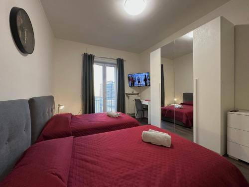 a bedroom with two beds with red sheets and a mirror at Suite Rossini - 100mq con parcheggio gratuito in Alessandria