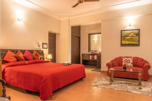 een grote slaapkamer met een rood bed en een stoel bij The Horizon Villa Dharamshala in Dharmsala