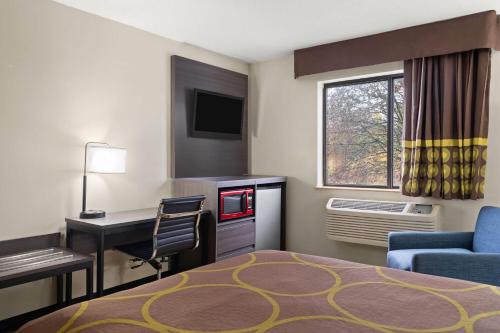 a hotel room with a bed and a desk and a computer at Super 8 by Wyndham Hagerstown I-70 in Hagerstown