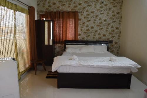 a bedroom with a bed with white sheets and pillows at Aakruthi Homestay in Dāvangere