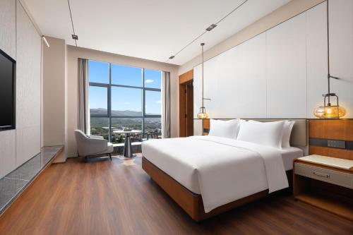 ein Schlafzimmer mit einem weißen Bett und einem großen Fenster in der Unterkunft Wyndham Garden Linxia Downtown in Linxia