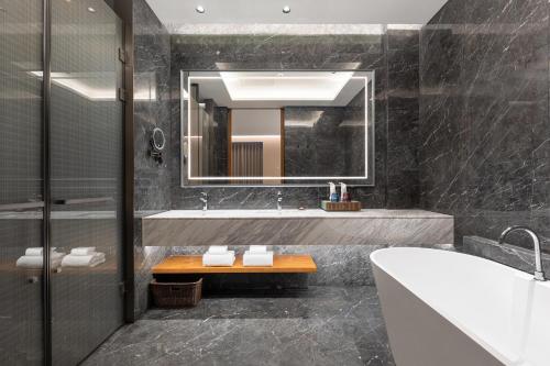 ein Badezimmer mit Badewanne, Waschbecken und Spiegel in der Unterkunft Wyndham Garden Linxia Downtown in Linxia