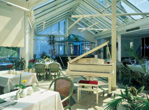 a white piano in a restaurant with tables and chairs at Hotel Fährkrug in Templin