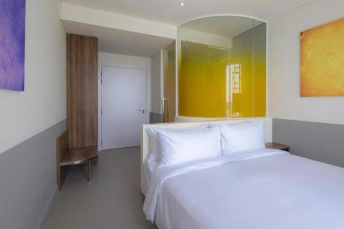 a bedroom with a white bed and a mirror at Wink Hai Phong Centre, Unscripted by Hyatt in Hai Phong