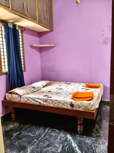 a small bed in a room with a purple wall at M R ViLLA HAMPI magic rock villa in Hampi