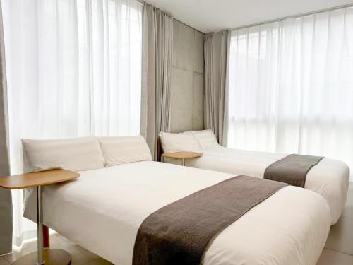 two beds in a hotel room with a window at 201Room,7-minute walk from Uguisudani Station located on the 2nd floor of an apartment-style building Twin room No elevator in Tokyo