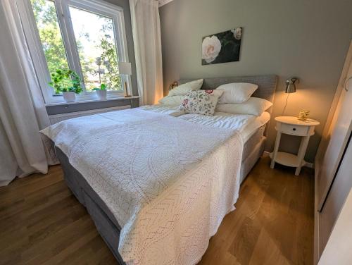 a bedroom with a bed with a white comforter and two windows at Host Harmony 6 PP Cabin Close to lake in Vittsjö
