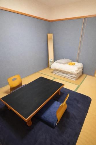 een kamer met een tafel en een bed bij 宿屋しの軒 1階 in Kirishima
