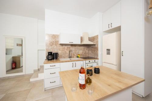 a kitchen with white cabinets and a wooden table with wine bottles at Villa Castillo Ena in Agios Nikolaos