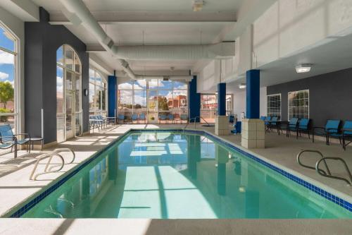 a swimming pool in a building with chairs and tables at La Quinta by Wyndham Gallup in Gallup