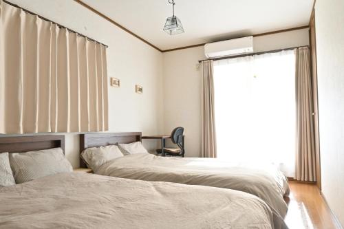 two beds in a bedroom with a window at Villa Izumi Eternity and a Day 一棟貸し民泊いずみの宿永遠と一日 in Izumi