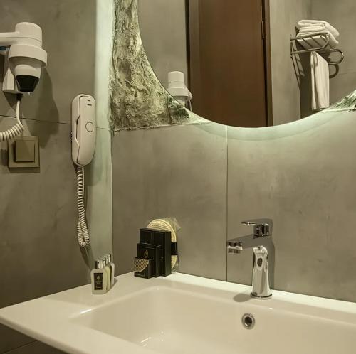 ein Badezimmer mit einem Waschbecken mit einem Telefon und einem Spiegel in der Unterkunft The Erzurum Hotel in Erzurum