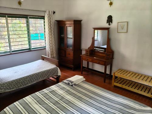 een slaapkamer met twee bedden, een ladekast en een spiegel bij Under the Tamarind in Bangalore