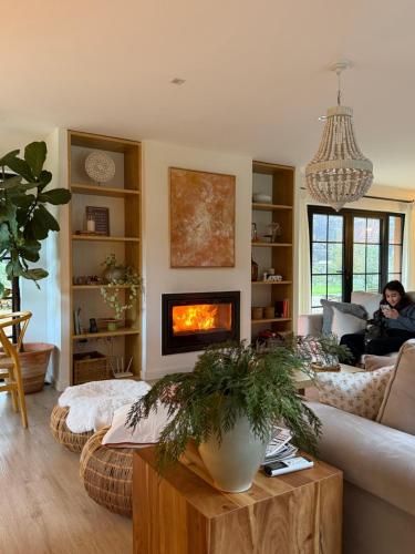 a woman sitting on a couch in a living room with a fireplace at Quinta das Levadas - Country House & Nature in Alvoco das Várzeas