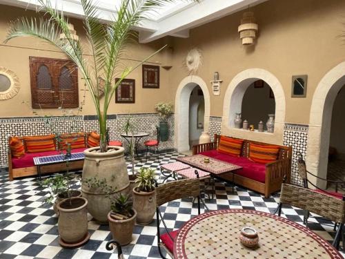 un soggiorno con divani e palme in un edificio di Appartement Riad Sidi Magdoul a Essaouira