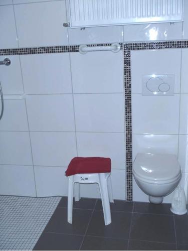 a bathroom with a toilet and a stool next to a sink at Landhotel Spessartruh in Frammersbach