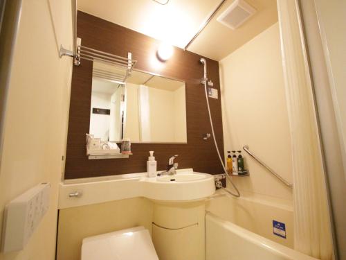 a bathroom with a sink and a toilet and a mirror at APA Hotel Komatsu in Komatsu