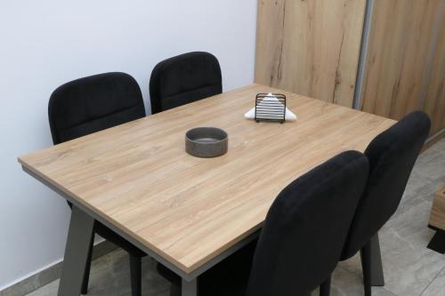 a wooden table with four chairs and a black box on it at Emily Apartments 3 in Chrysoupolis