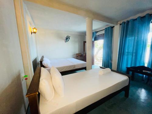 a bedroom with two beds with blue curtains at Can win Resort Yala in Tissamaharama