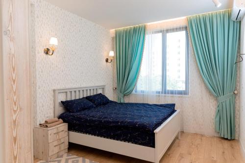 een slaapkamer met een bed met blauwe lakens en een raam bij Lavender H in Khujand