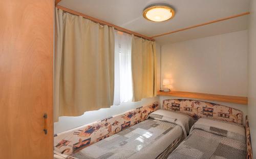 a small room with two beds in front of a window at Camping Parco Vacanza Partaccia 2 in Marina di Massa