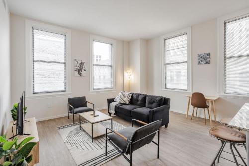 een woonkamer met een zwarte bank en stoelen bij CozySuites Sky Central #4 in Cincinnati