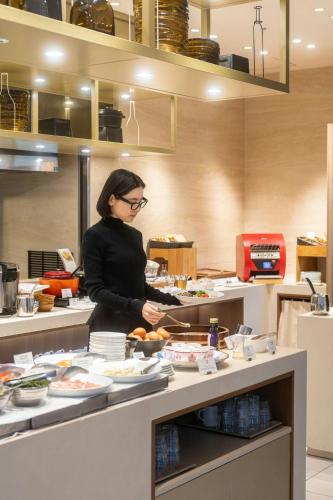 a woman standing in a kitchen preparing food at Courtyard by Marriott Osaka Honmachi in Osaka