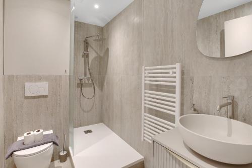 een badkamer met een wastafel, een toilet en een spiegel bij Charmant et central - Neuilly in Neuilly-sur-Seine