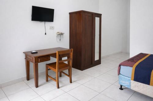 a bedroom with a desk and a bed and a television at Hotel Danau Indah By ARBA in Cibuntu