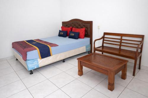 a bedroom with a bed and a chair and a table at Hotel Danau Indah By ARBA in Cibuntu