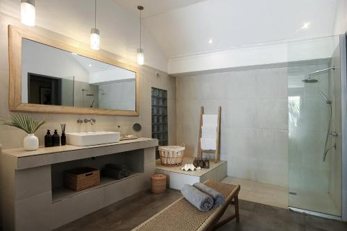 een badkamer met een wastafel en een spiegel en een douche bij Indiana Kenanga Boutique Hotel & Spa in Nusa Lembongan