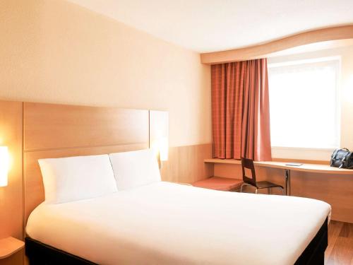a hotel room with a bed and a desk and a window at ibis Bristol Centre in Bristol