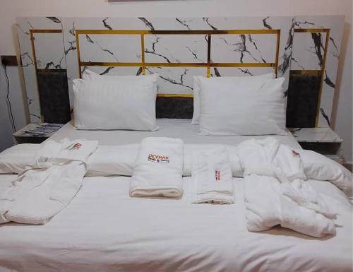 een bed met witte lakens en handdoeken erop bij DEVHAK Hotel and Suites in Warri